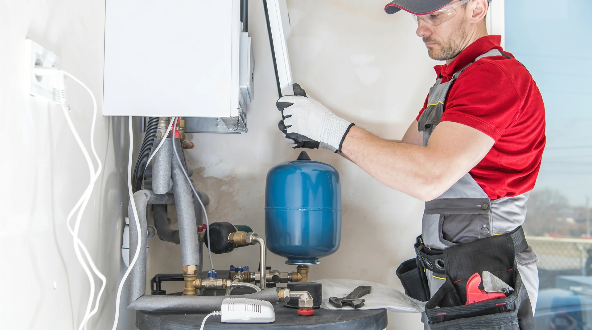 Technicien en plomberie intervenant sur installation de chauffage domestique dans local technique résidentiel