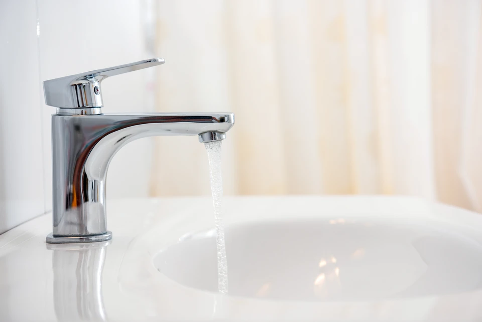 Salle de bain moderne avec lavabo et miroir, serviette blanche suspendue à un porte-serviettes annulaire chromé