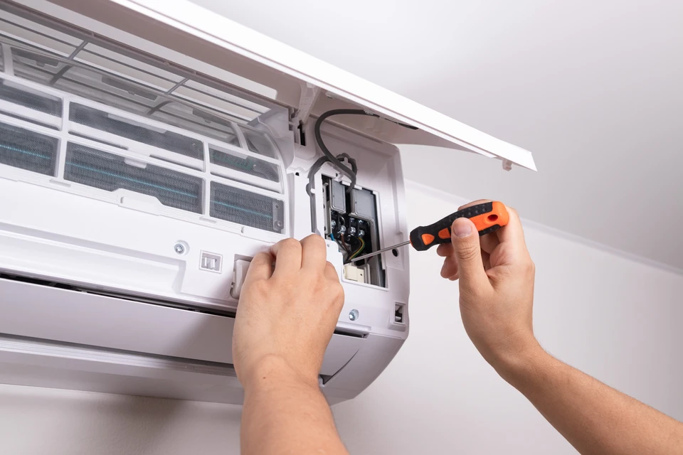 Technicien chauffagiste qualifié en uniformité professionnelle, effectuant l'entretien ou la réparation d'une chaudière gaz ou d'une pompe à chaleur air/air dans l'intérieur d'une maison résidentielle. Le technicien manipule les équipements avec professionnalisme, mettant en avant son expertise et sa présence rassurant auprès du client. L'image doit transmettre la confiance, la proximité et le professionnalisme d'un artisan local intervenant au domicile.