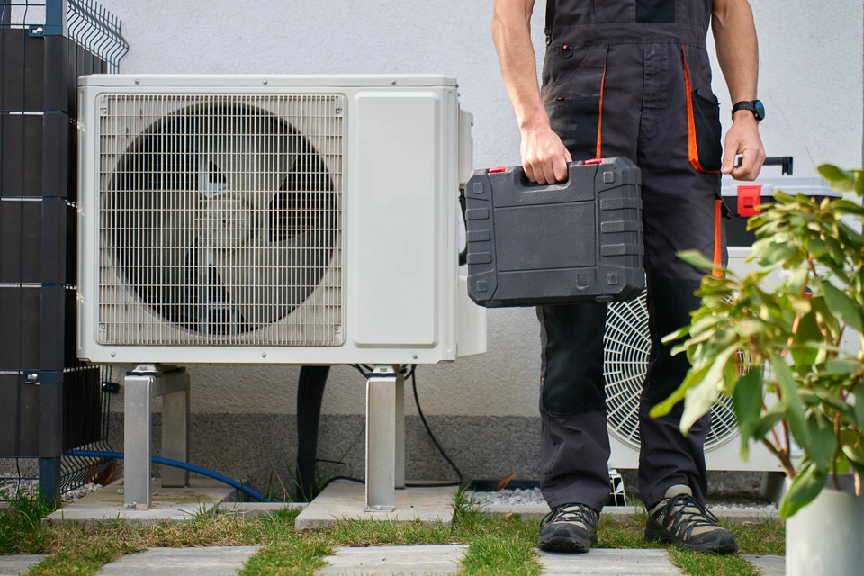 Technicien en climatisation travaillant à l'extérieur sur une pompe à chaleur ou climatiseur résidentiel