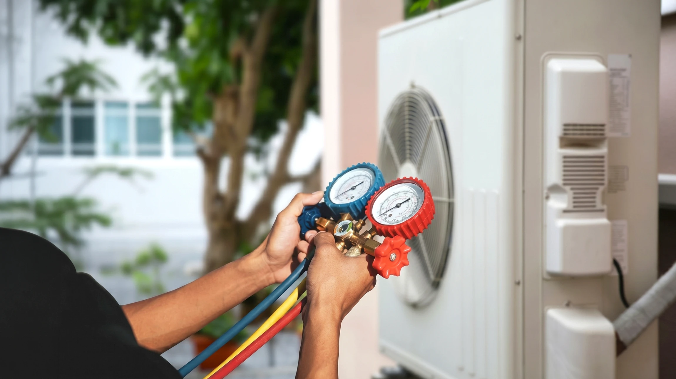 Technicien en uniform professionnel (polo ou combinaison) effectuant un diagnostic sur l'unité extérieure d'une pompe à chaleur air-air ou air-eau résidentielle. Le technicien utilise un appareil de diagnostic ou de mesure adapté. La scène se déroule devant une maison résidentielle avec la pompe à chaleur visible et bien positionnée. L'image doit transmettre professionnalisme, expertise technique et proximité avec le client dans son environnement domestique.