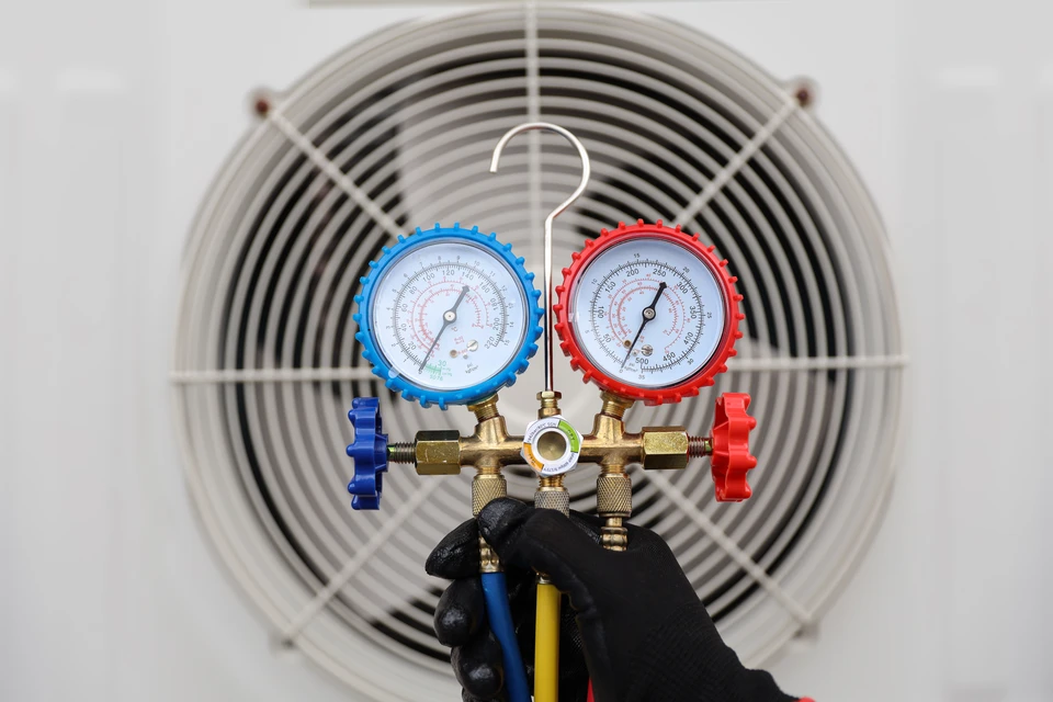 Technicien HVAC en uniforme vert travaillant sur système de chauffage/climatisation dans intérieur résidentiel