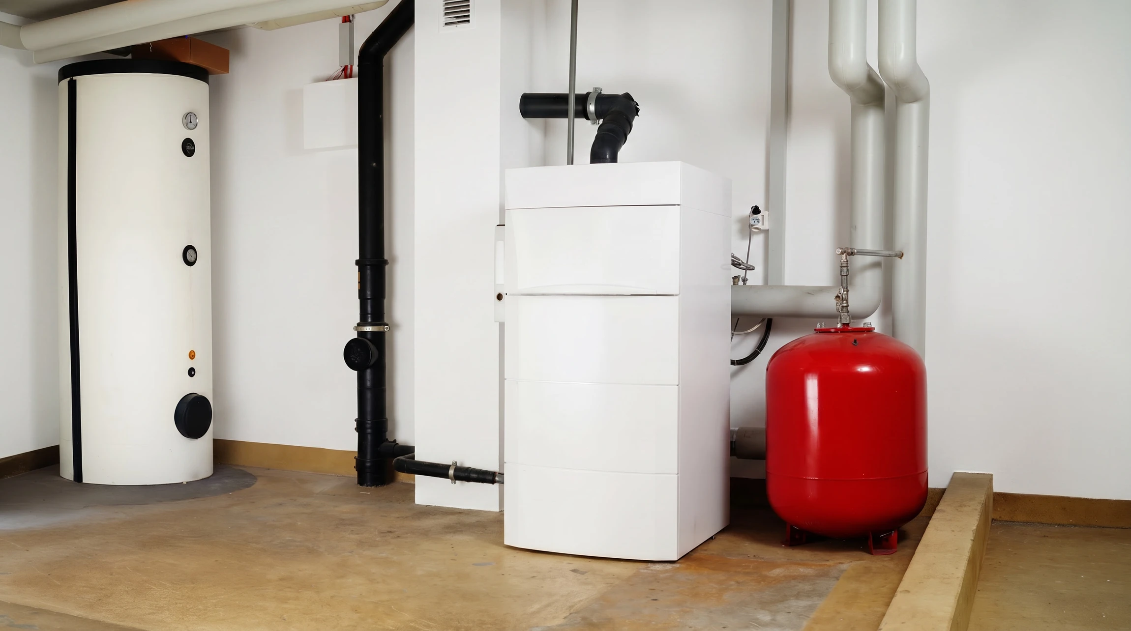 Technicien en plomberie travaillant dans une chaufferie résidentielle, ajustant une canalisation avec une clé à molette rouge