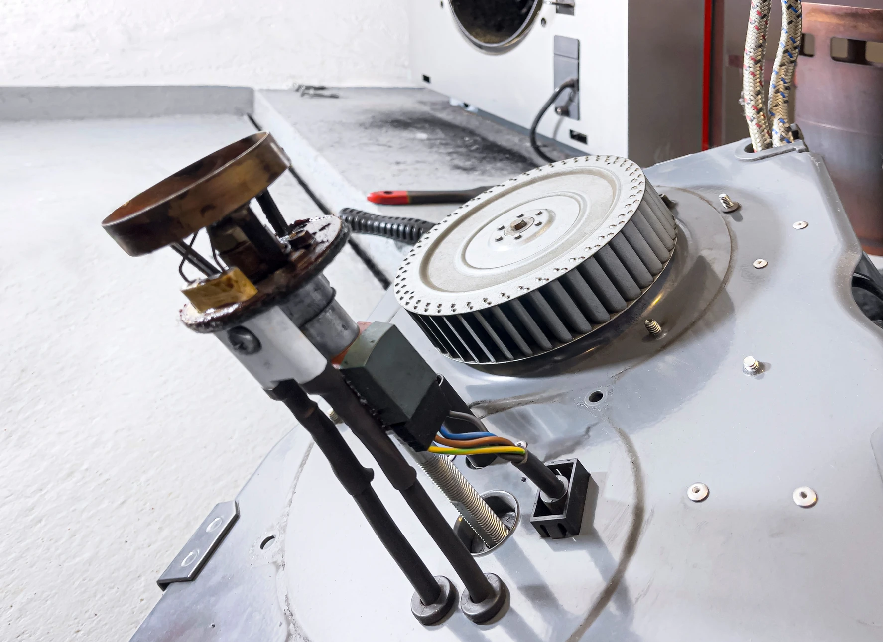 Un technicien en tenue professionnelle effectuant une visite d'entretien annuel d'une chaudière chez un client, en train de vérifier les paramètres de la chaudière avec un outil de diagnostic, dans un intérieur résidentiel. Le technicien montre les relevés ou explique le contrôle au propriétaire, illustrant ainsi le suivi de qualité et la relation de confiance dans la durée.